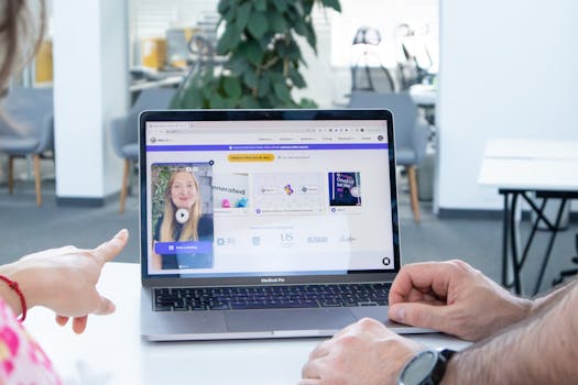 Two colleagues working together on a laptop screen in a modern office setting.