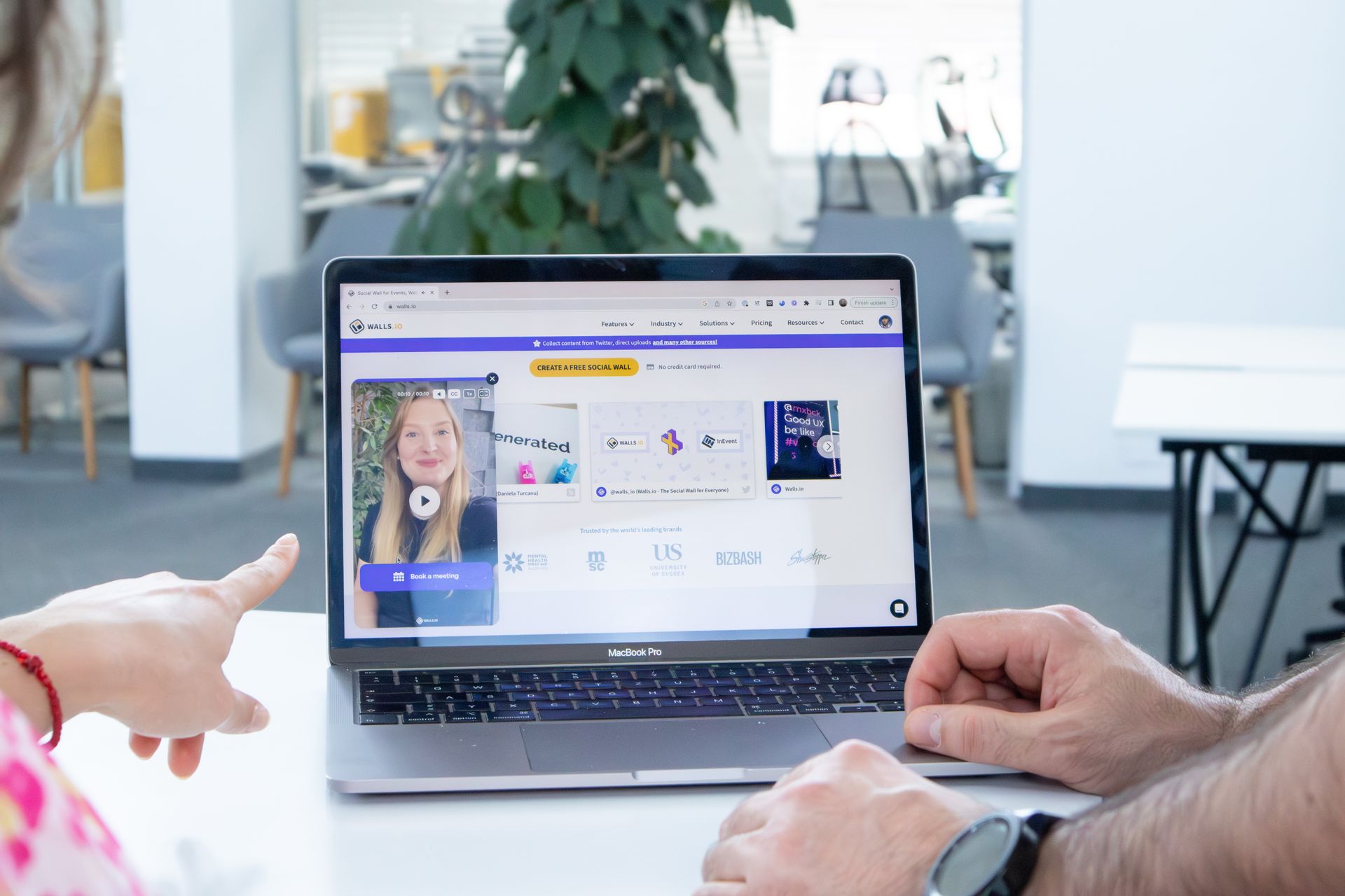 Two colleagues working together on a laptop screen in a modern office setting.