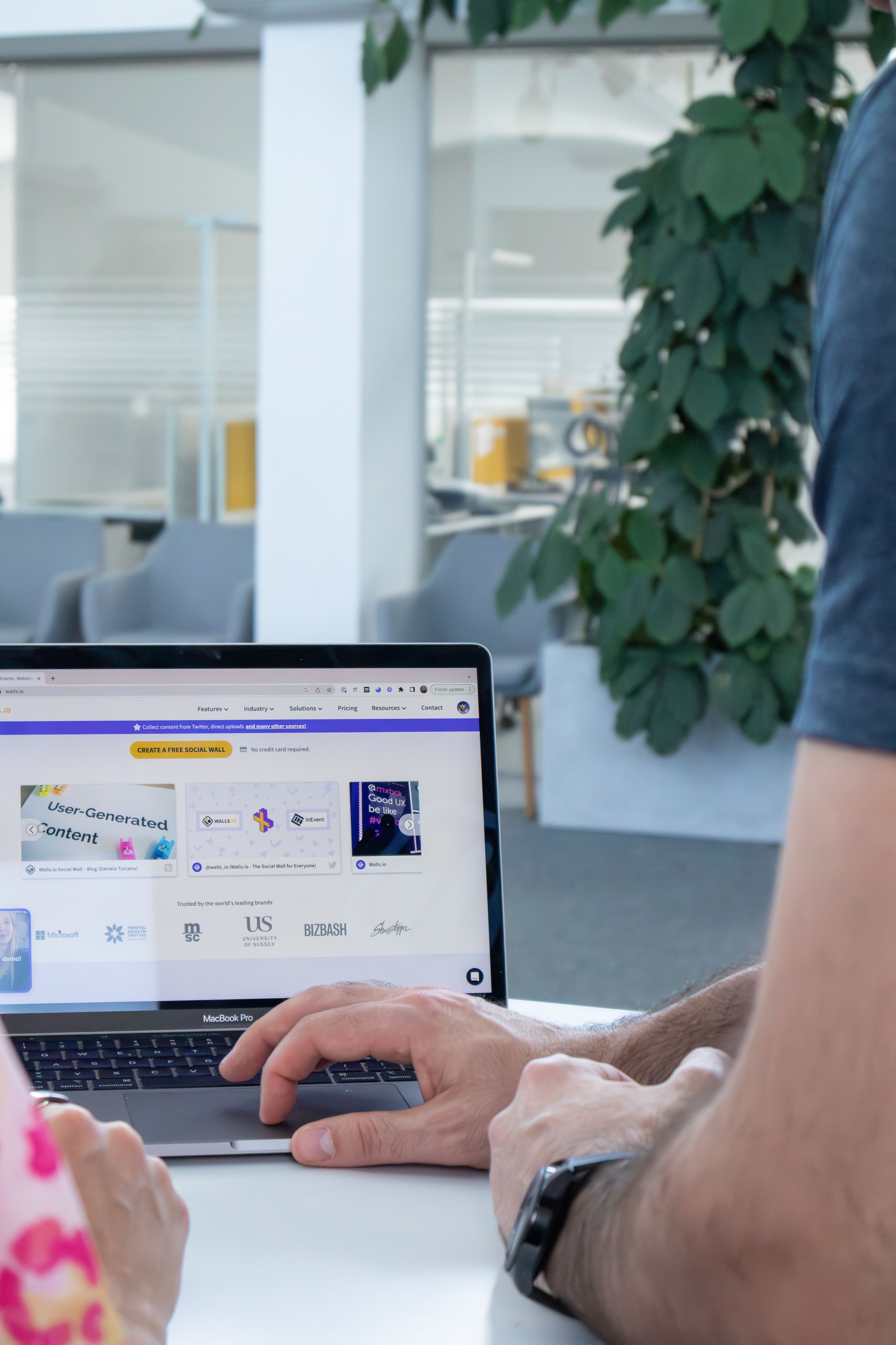 Adults collaborating in a modern office, using a laptop computer.