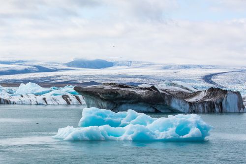 Free Stunning iceberg floating peacefully in the cold Arctic waters against a snowy backdrop. Stock Photo