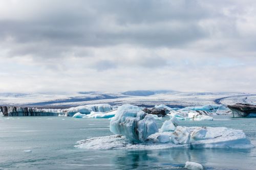 Free Stunning view of icebergs floating in icy water with snowy backdrop under cloudy sky. Stock Photo