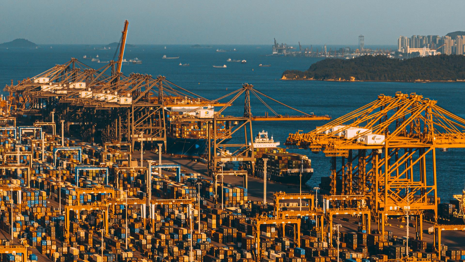 Aerial shot of Xiamen Port in China showcasing cranes and cargo containers by the sea.