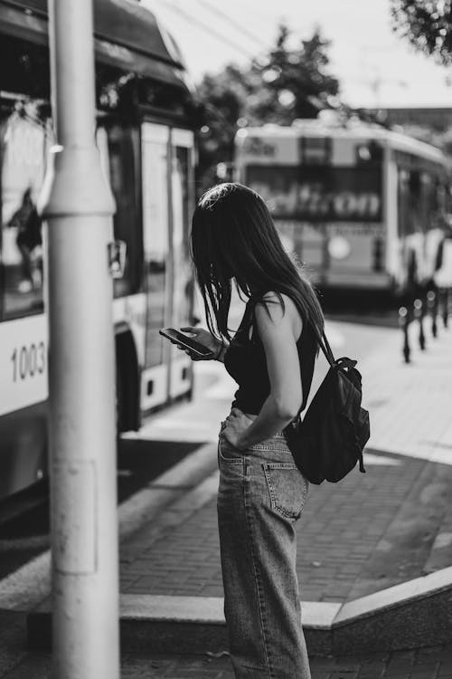 Black and white photo of a girl sitting at the bus station