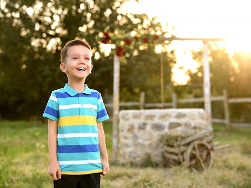 A Happy Little Boy Standing Outside at Sunset 