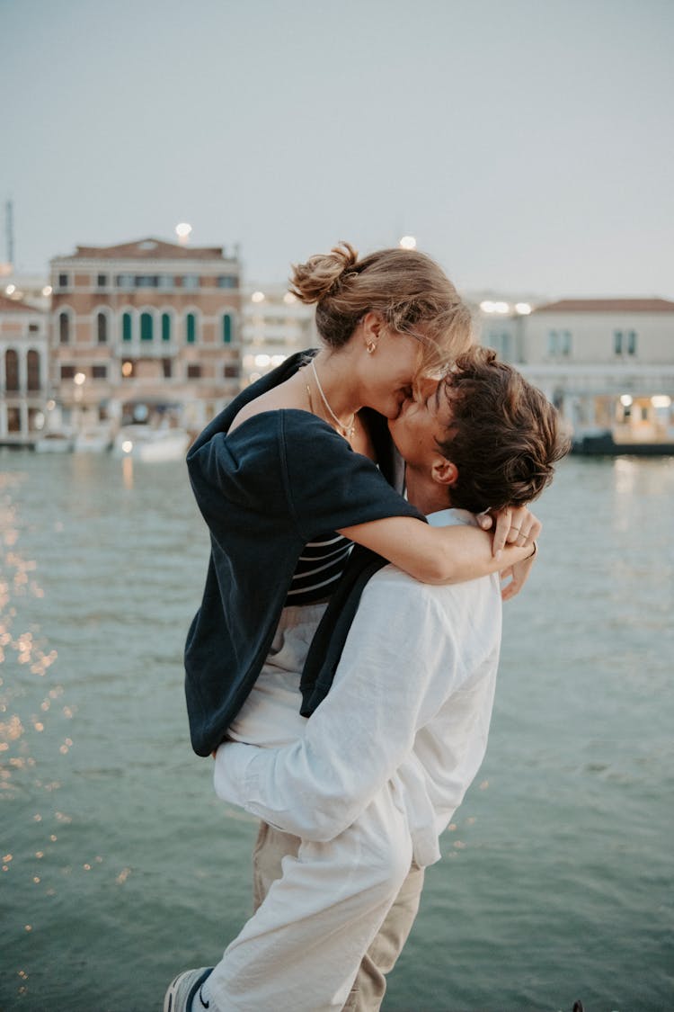 Man Holding Woman In Arms Kissing On Sunset