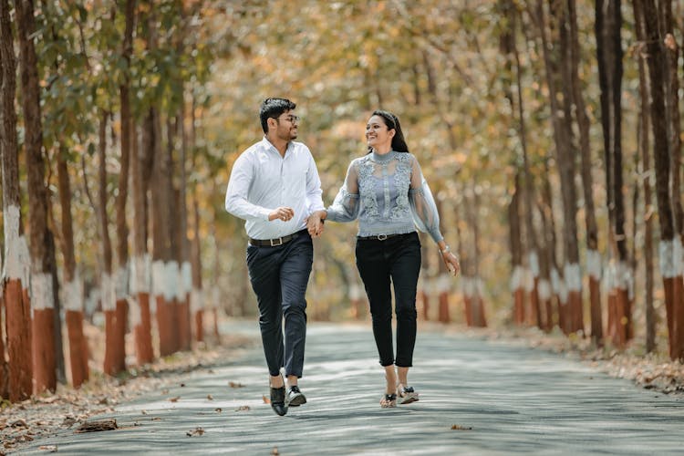 Young Happy Couple Walking On A Road In A Park