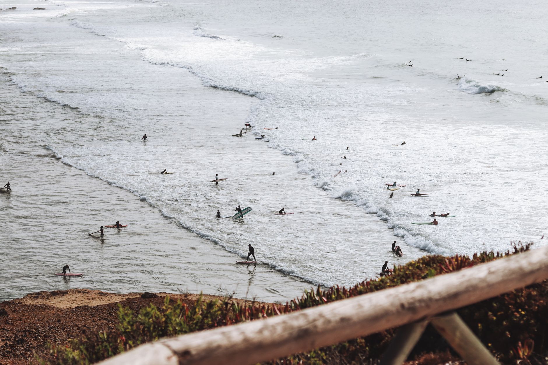High angle view capturing surfers riding waves, showcasing vibrant beach life and ocean scenery.