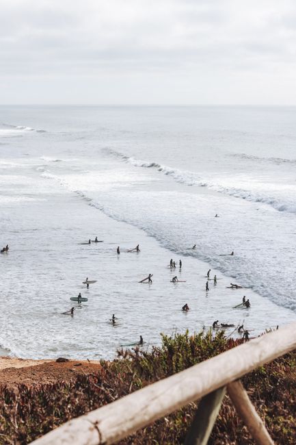 A vibrant scene of surfers riding waves on a cloudy day, capturing the essence of seaside adventure.