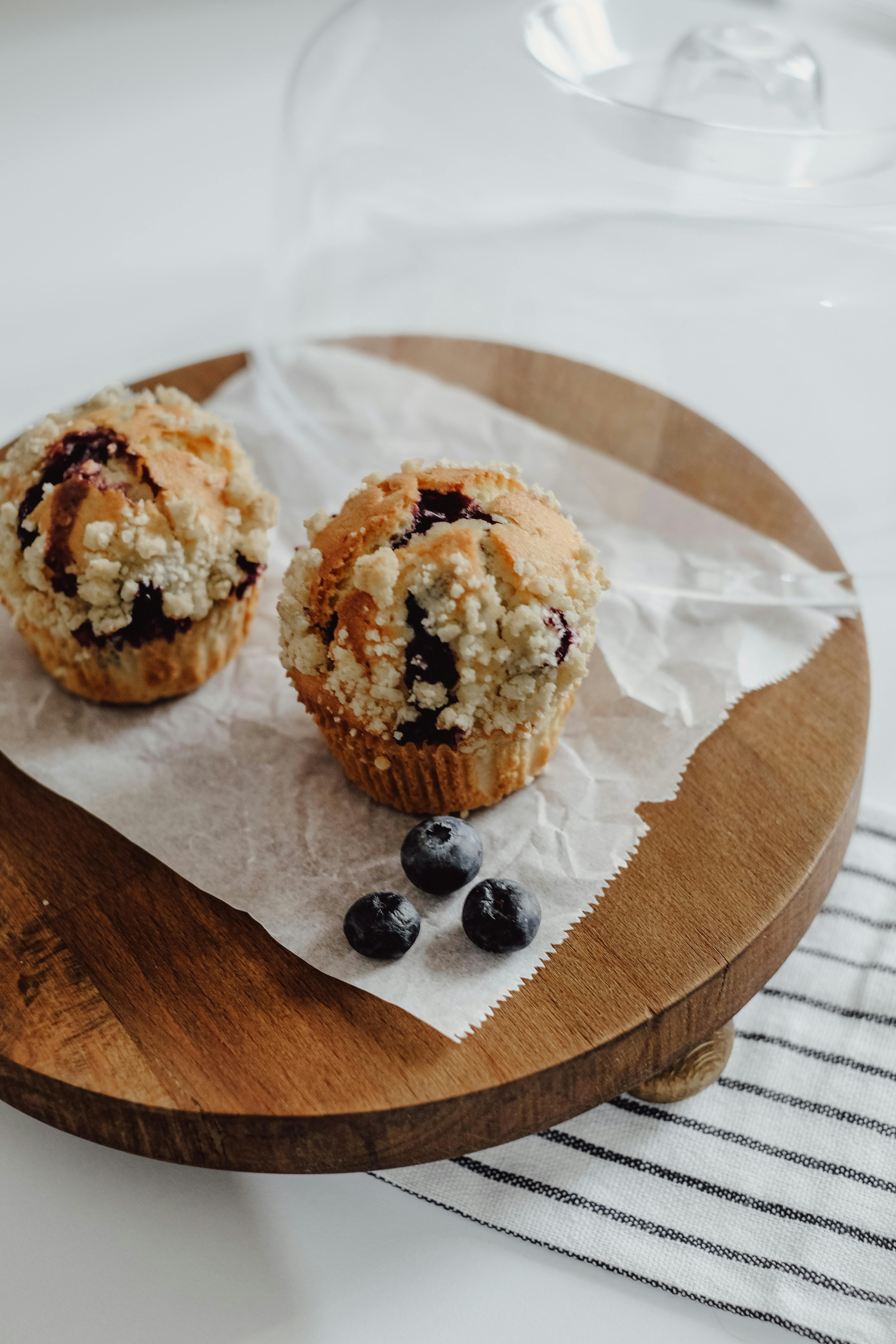 Close-up of freshly baked blueberry muffins with crumb topping on a wooden tray.