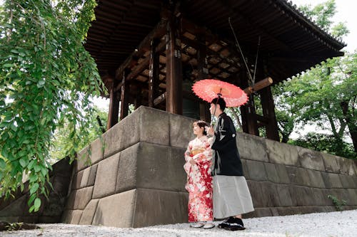 Young Couple Wearing Traditional Clothing Standing in front of a Wooden Gazebo