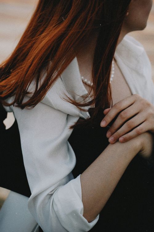Free Capture of redhead woman in white shirt sitting gracefully as sun sets. Stylish and timeless fashion image. Stock Photo