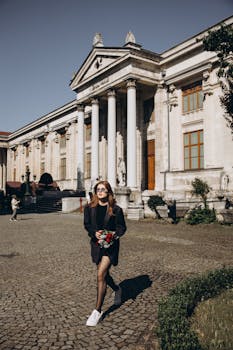 A stylish woman walking outside the Istanbul Archaeological Museum on a sunny day.