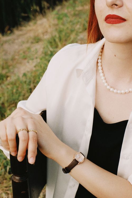 Free Close-up of a young woman wearing a pearl necklace and wristwatch with red lips outdoors. Stock Photo