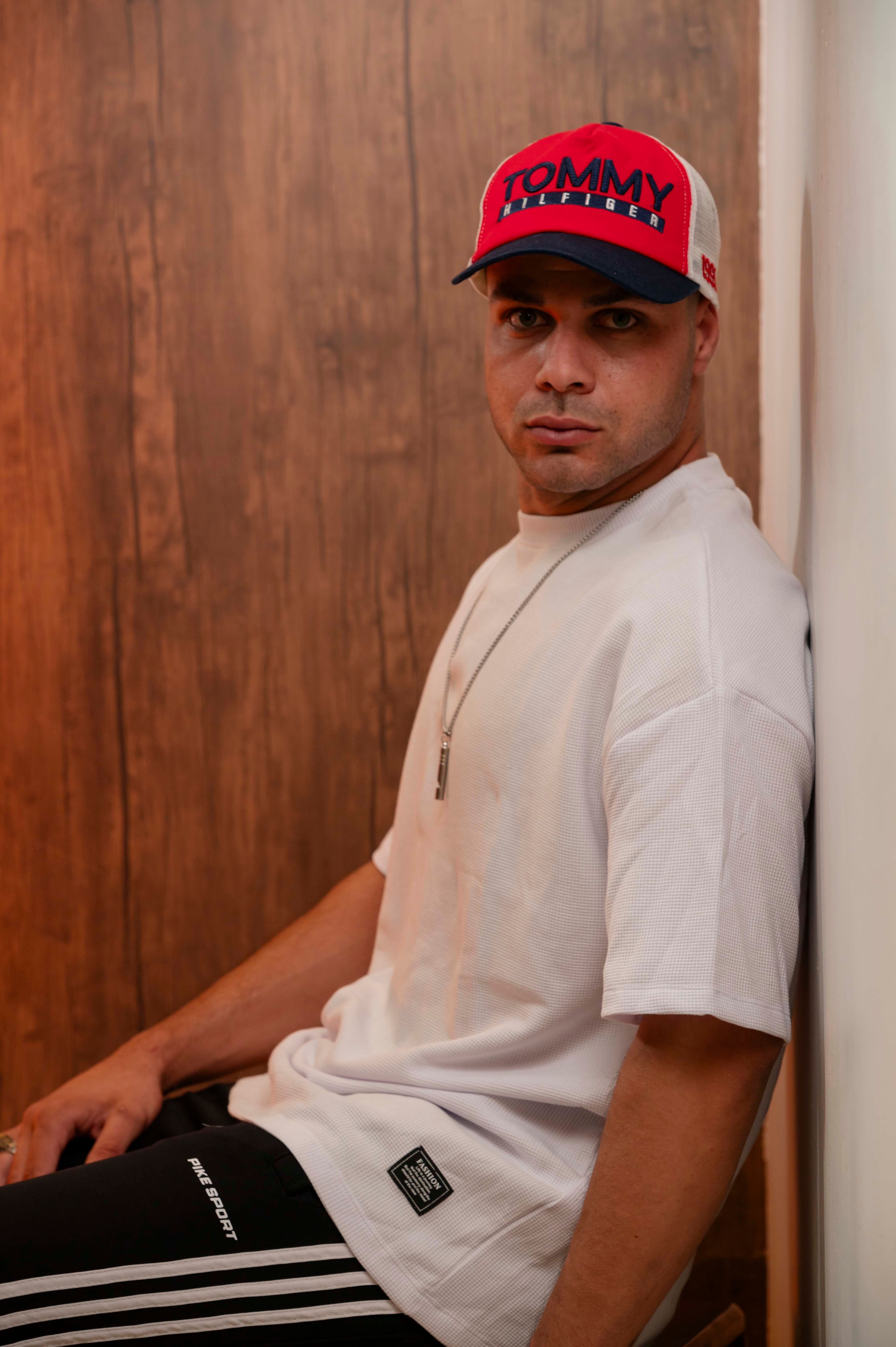 Fashionable man posing casually indoors wearing a red cap.