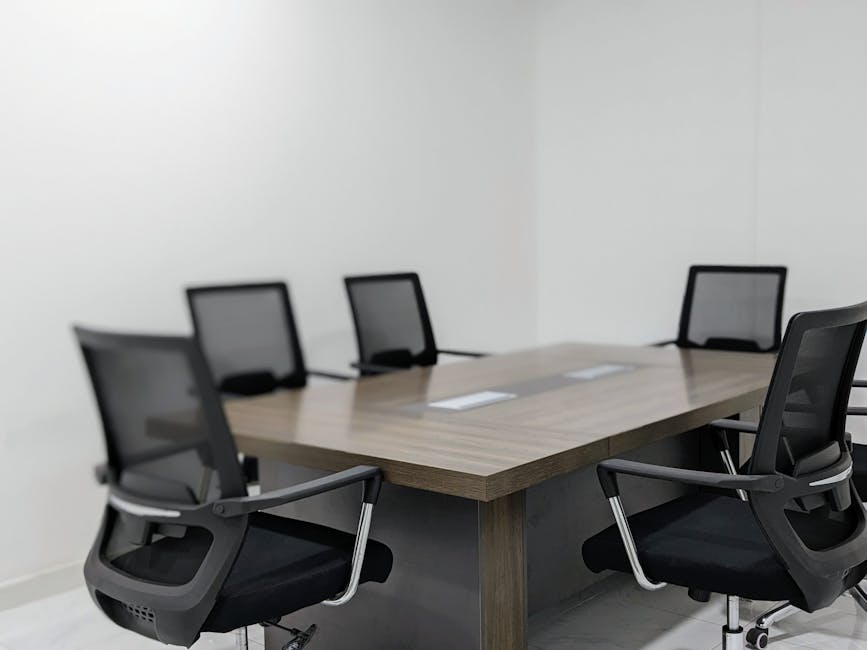 Empty modern office conference room featuring sleek black chairs and a wooden table.