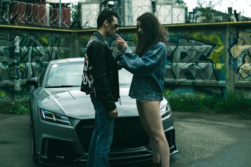 Woman and Man Lighting a Cigarette in front of a Car 