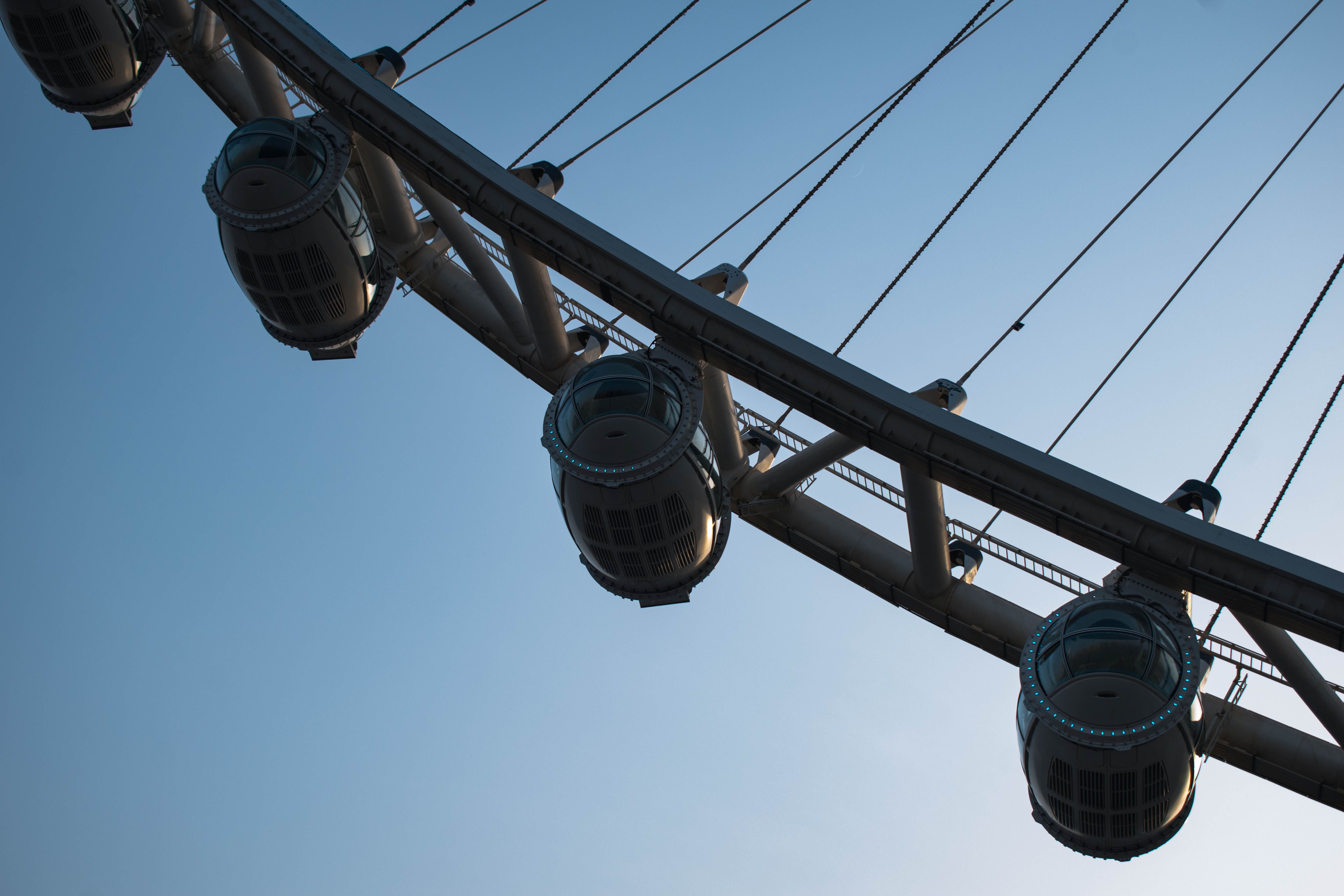 Partial view of a Ferris wheel against a clear blue sky in Dubai, showcasing capsules.
