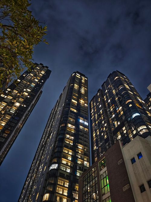 Free Night view of modern skyscrapers in Ho Chi Minh City, Vietnam, with illuminated windows under an overcast sky. Stock Photo