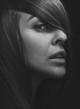 Artistic black and white portrait of a woman with long hair and captivating gaze.