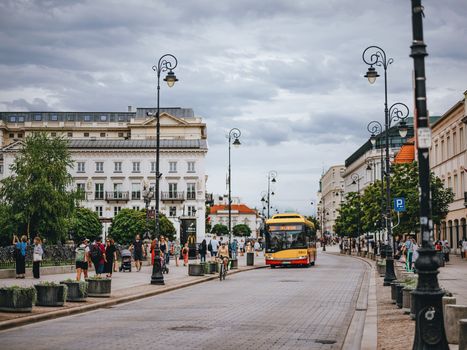 Bustling Warsaw street with modern bus and pedestrians, showcasing urban life.