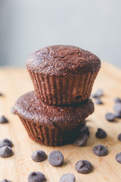 Free Close-up of chocolate cupcakes with scattered chocolate chips on a wooden surface. Stock Photo