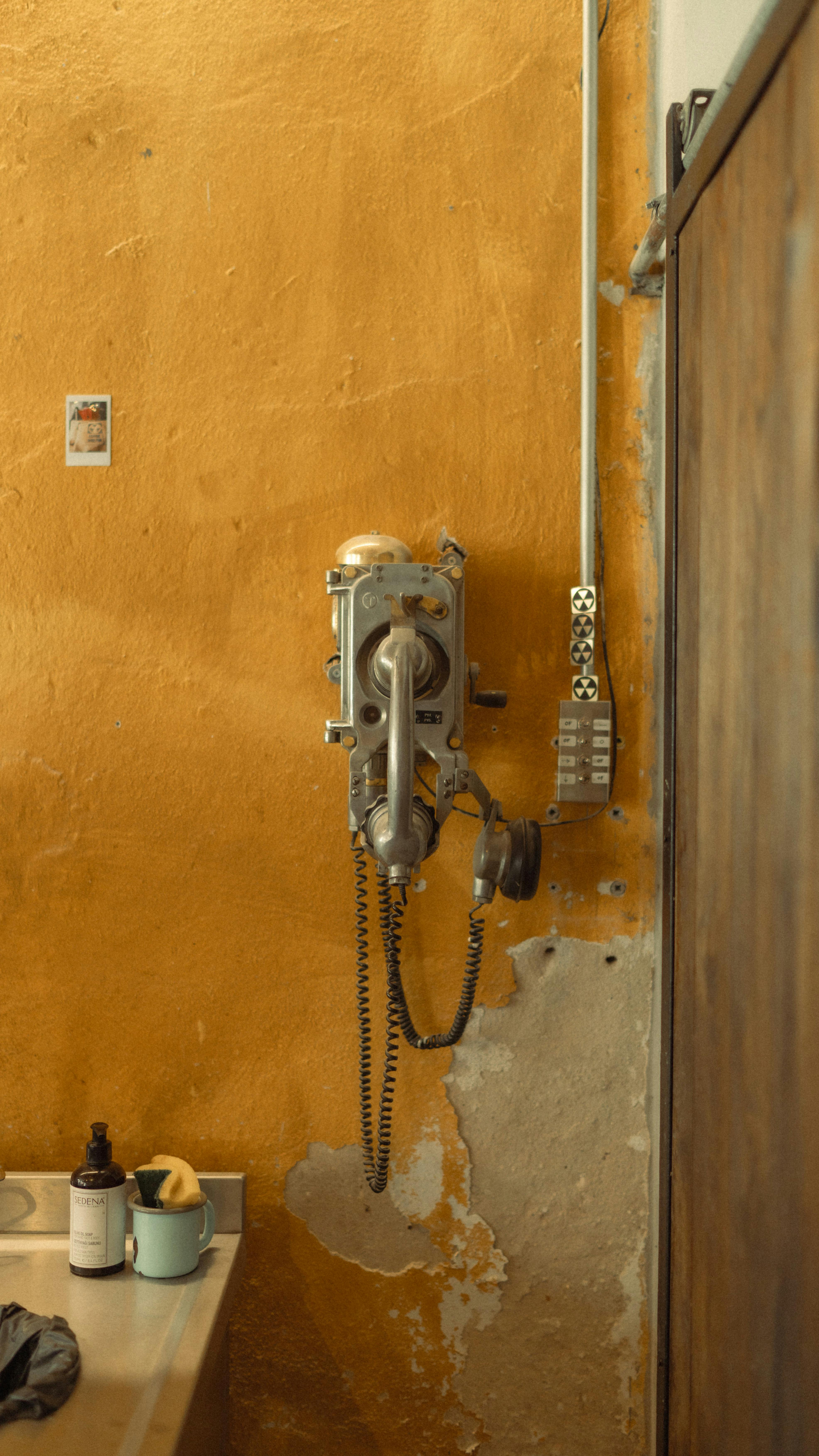 Retro wall-mounted telephone in a rustic interior in Bozcaada, Türkiye with worn plaster walls.