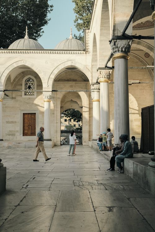 Free A serene view of people in a historic Istanbul mosque courtyard, capturing local life and architecture. Stock Photo