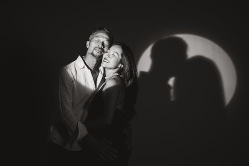 Black and White Photo of a Happy Man And Woman Standing Cheek to Cheek