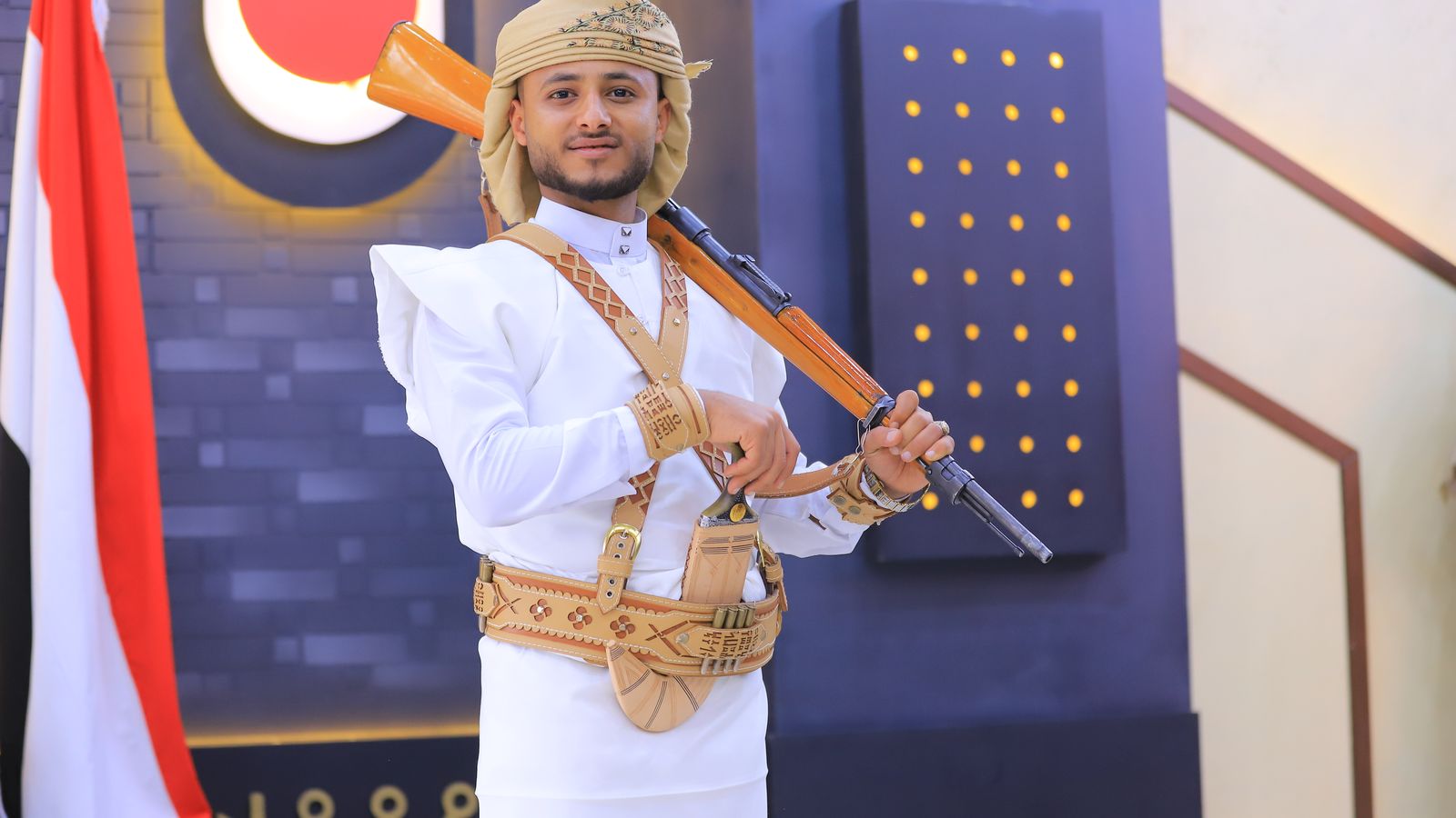 Traditionally dressed model in a beige turban and bandolier posing with a rifle on his shoulder and a jambiya dagger on his belt, Djibouti