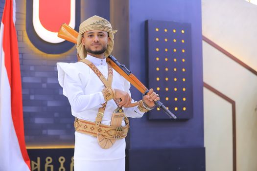 A man in traditional Yemeni dress poses with a rifle indoors in Sana'a, Yemen.