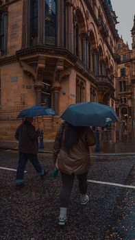 People with umbrellas walking on a rainy street in Manchester.