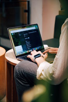 Adult using a laptop in a cozy cafe setting, showcasing modern work lifestyle.