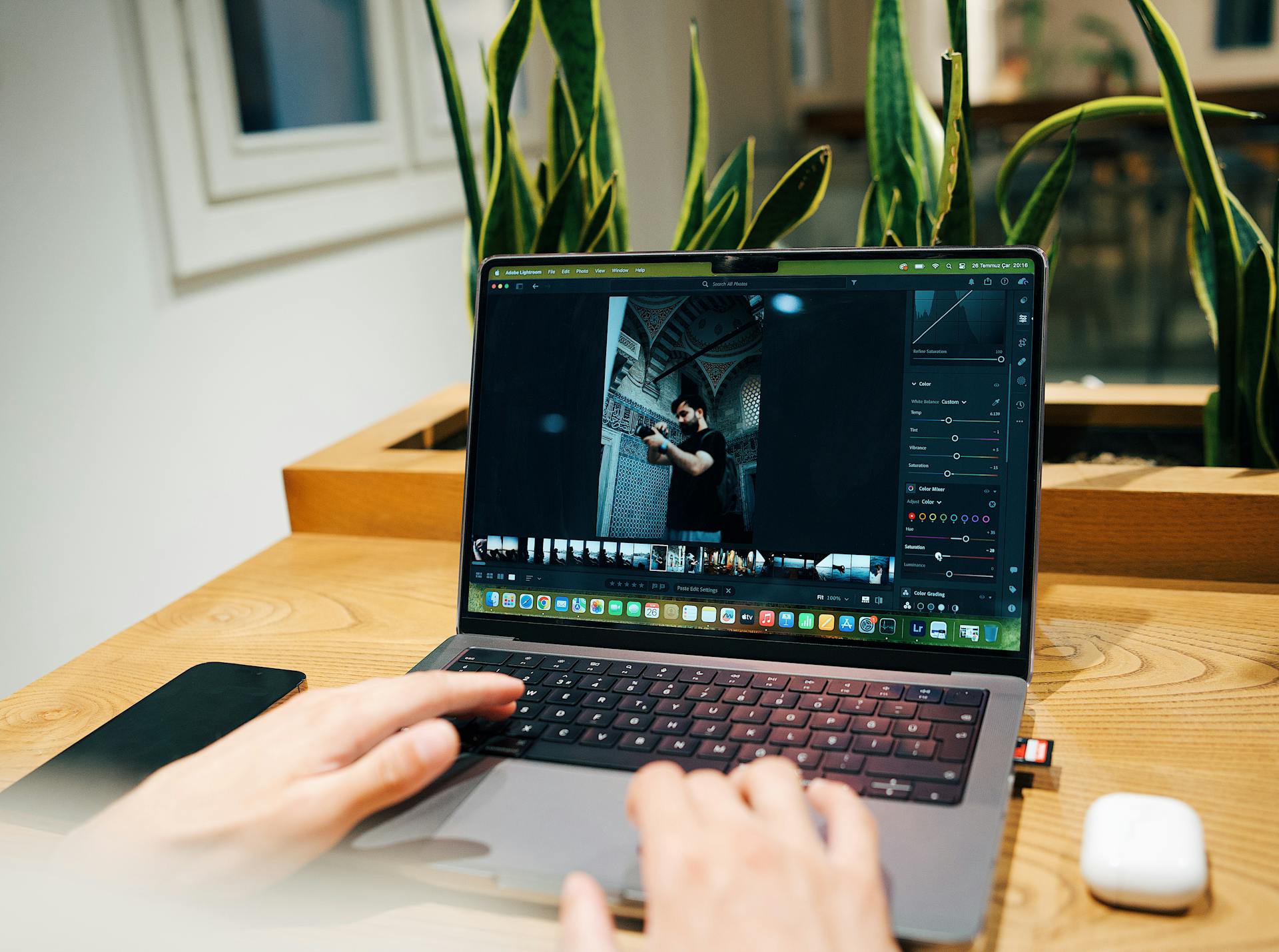 A photographer edits images on a laptop in a modern office setting.