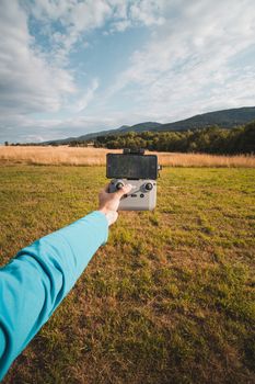Man controlling drone with a smartphone in a grassy field in Liberec, Czech Republic.