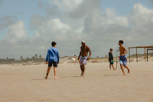 Free Four friends enjoying a game of soccer on a sunny summer beach. Stock Photo