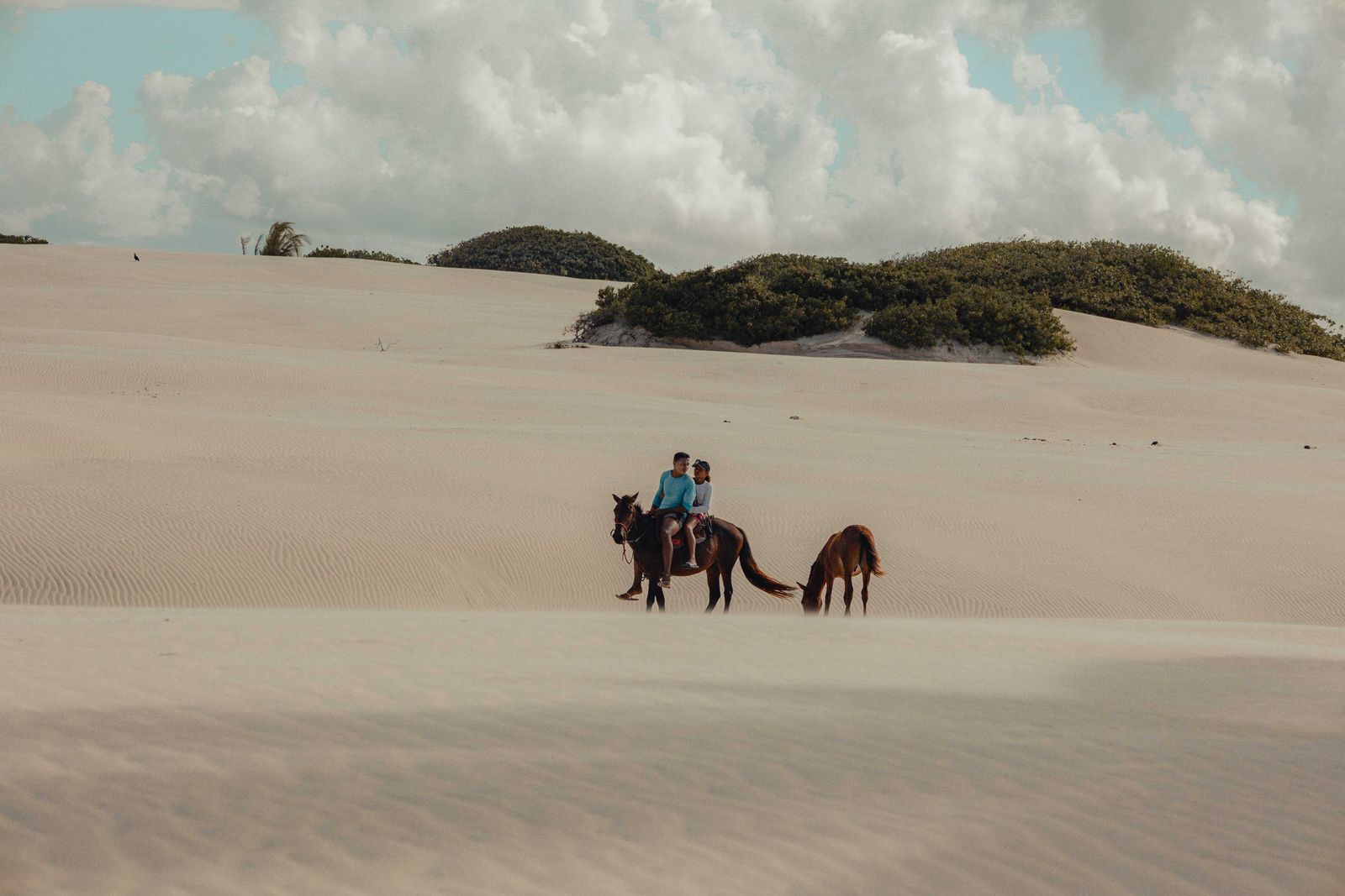 Two riders exploring wide sandy dunes