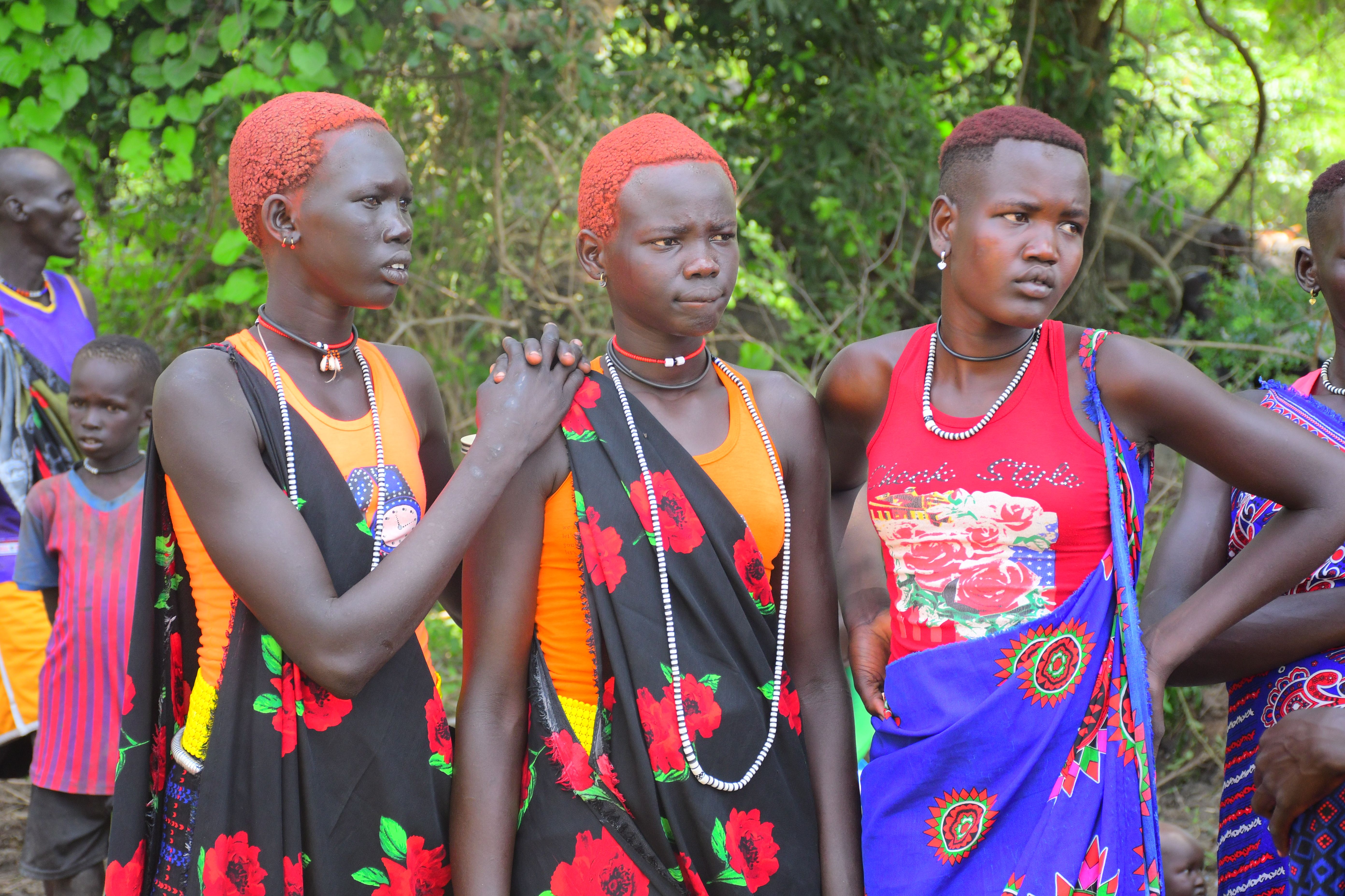 Teenage African girls celebrate at a cultural festival, wearing colorful garments and displaying traditional hairstyles.