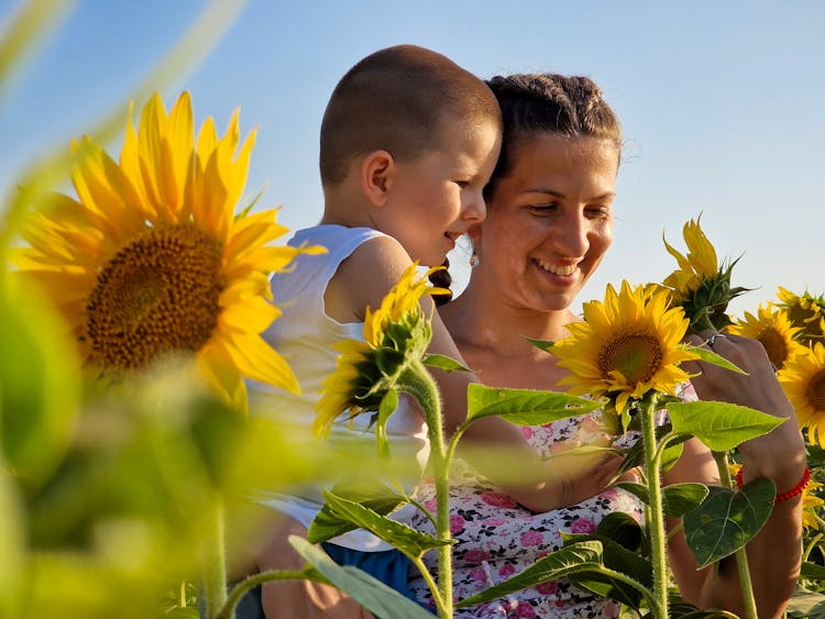 Smiling Mother With Son On Field Of Sunflowers