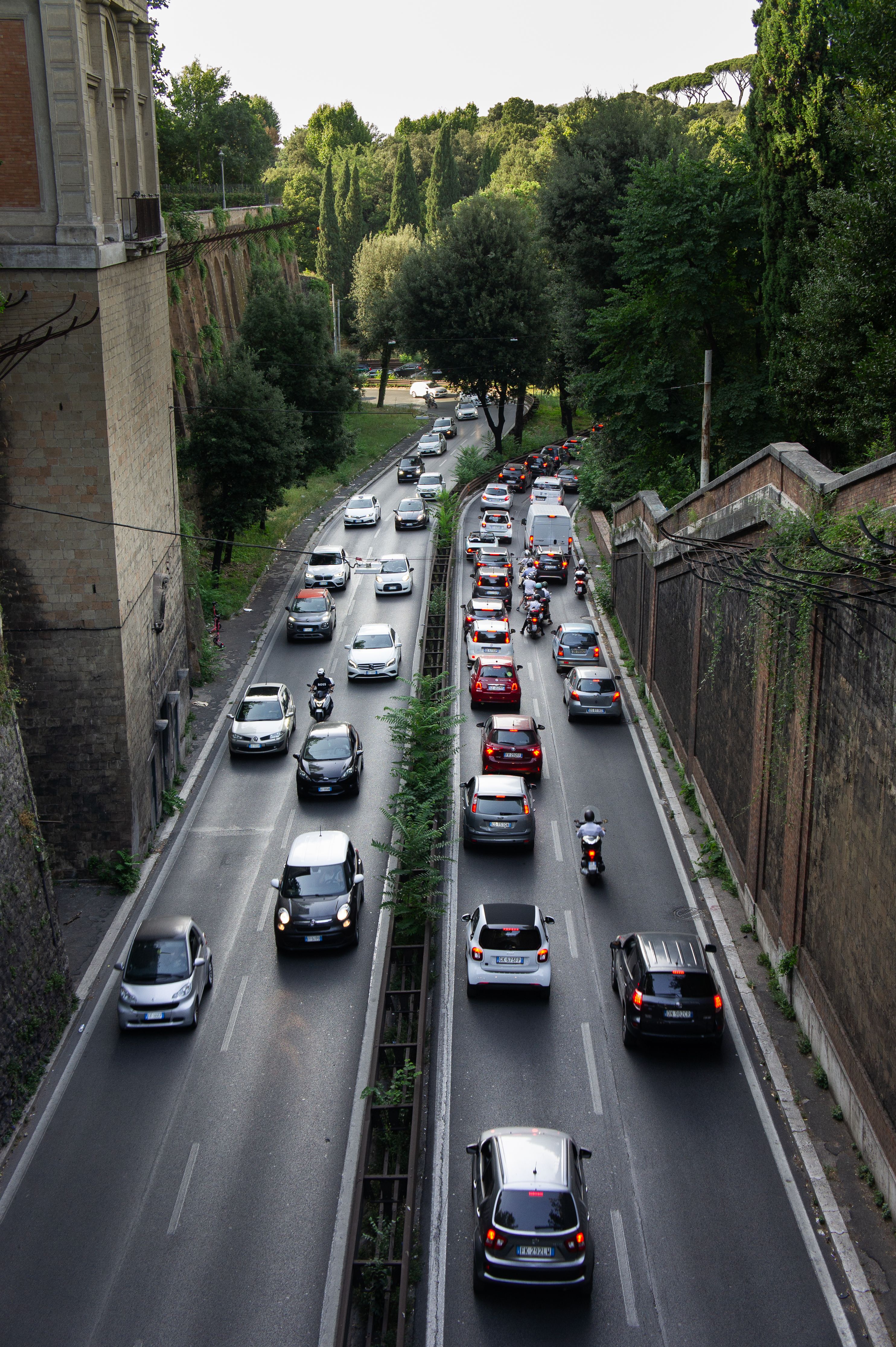 Aerial view of busy traffic in Rome with lush greenery and historic walls.