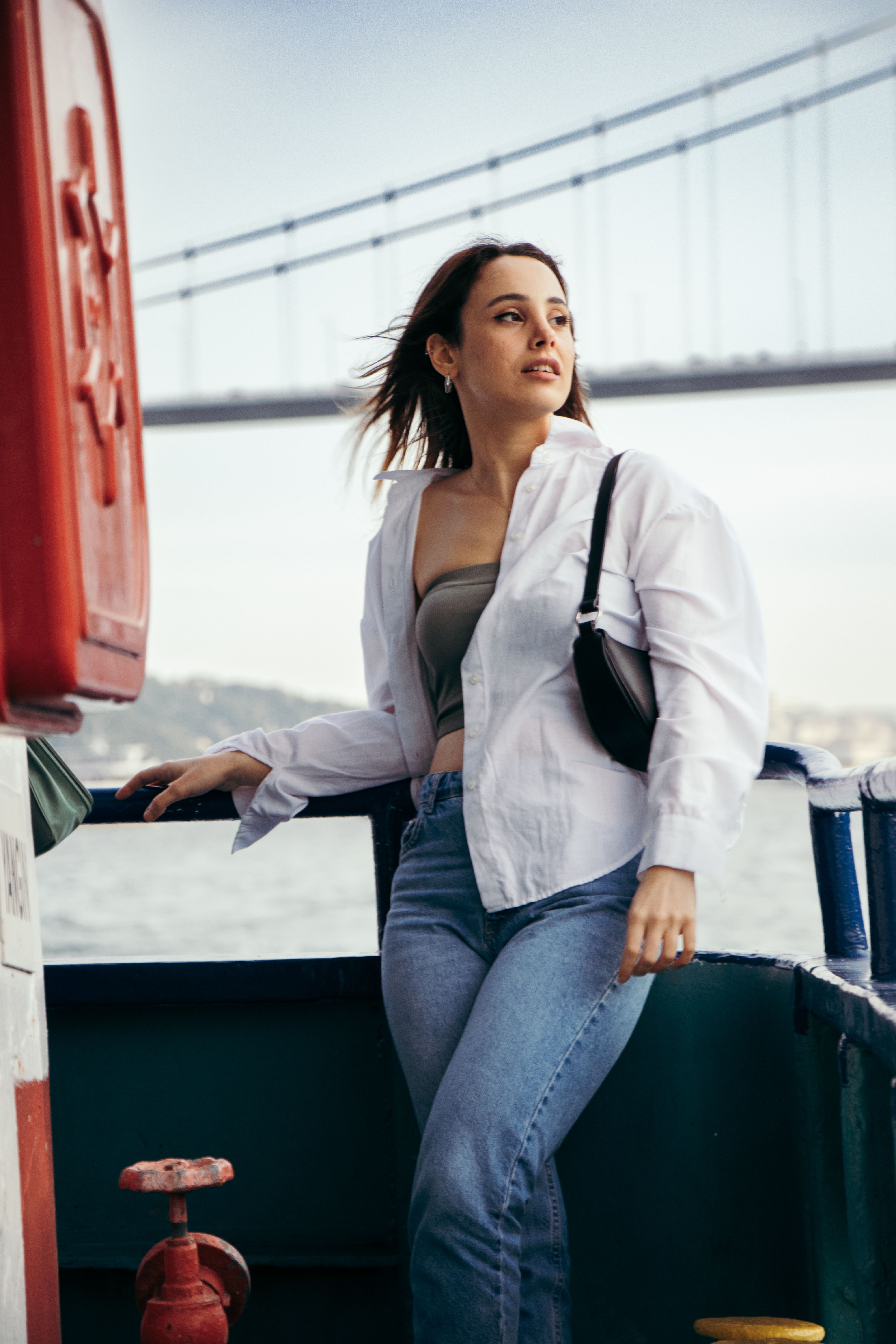 A young woman enjoys a relaxing boat ride with a scenic bridge view in the background.