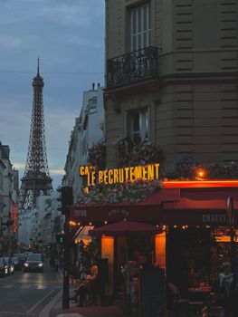 Charming Paris street scene with a café and Eiffel Tower illuminated at twilight.