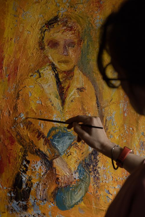 Free An artist's hand captures a portrait with a brush on a vibrant textured canvas. Stock Photo