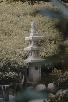 A traditional stone lantern amidst lush greenery in a tranquil Japanese garden setting.