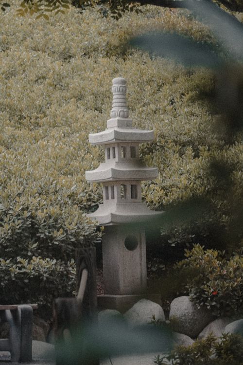 Free A traditional stone lantern amidst lush greenery in a tranquil Japanese garden setting. Stock Photo