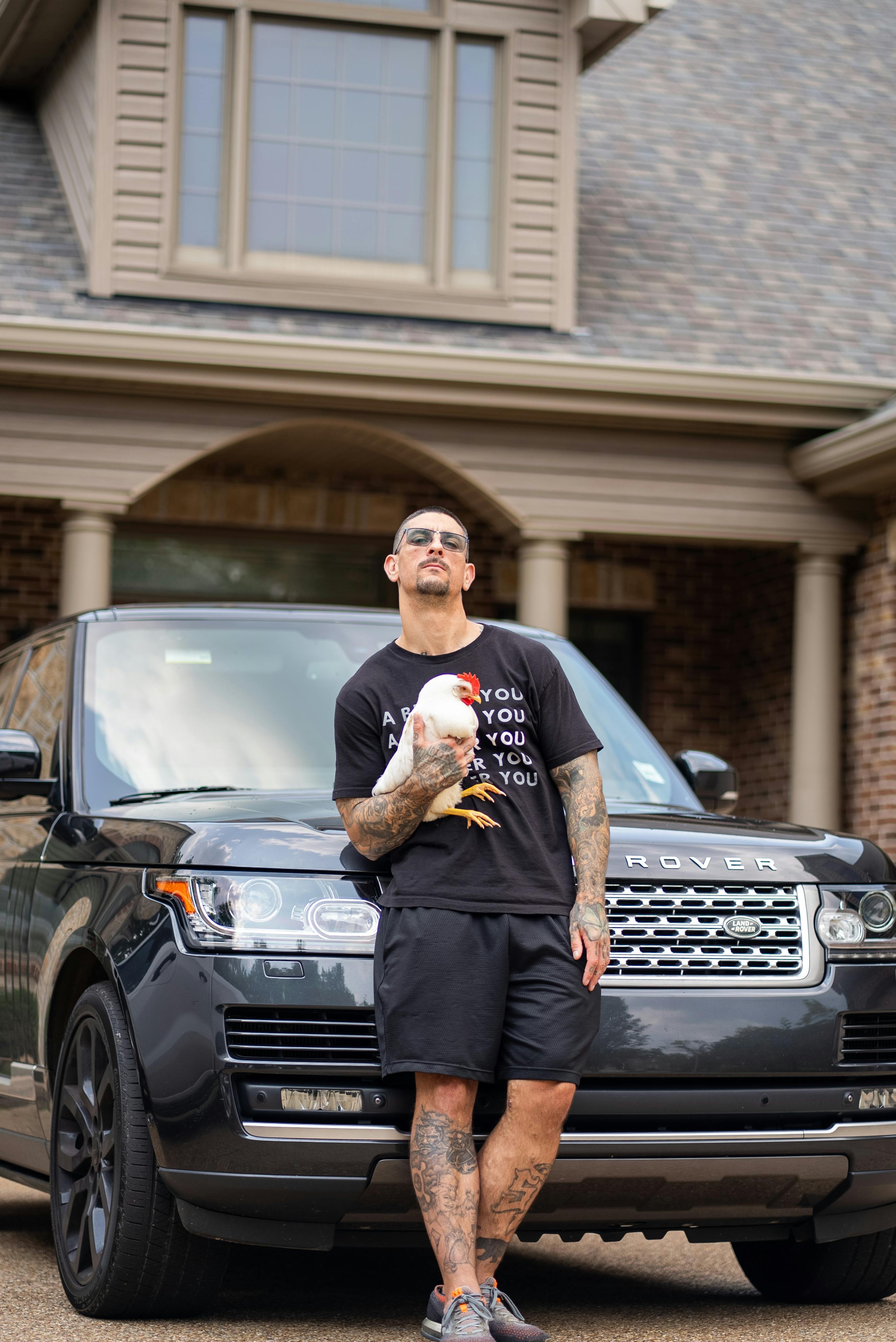 man with hen posing by black land rover