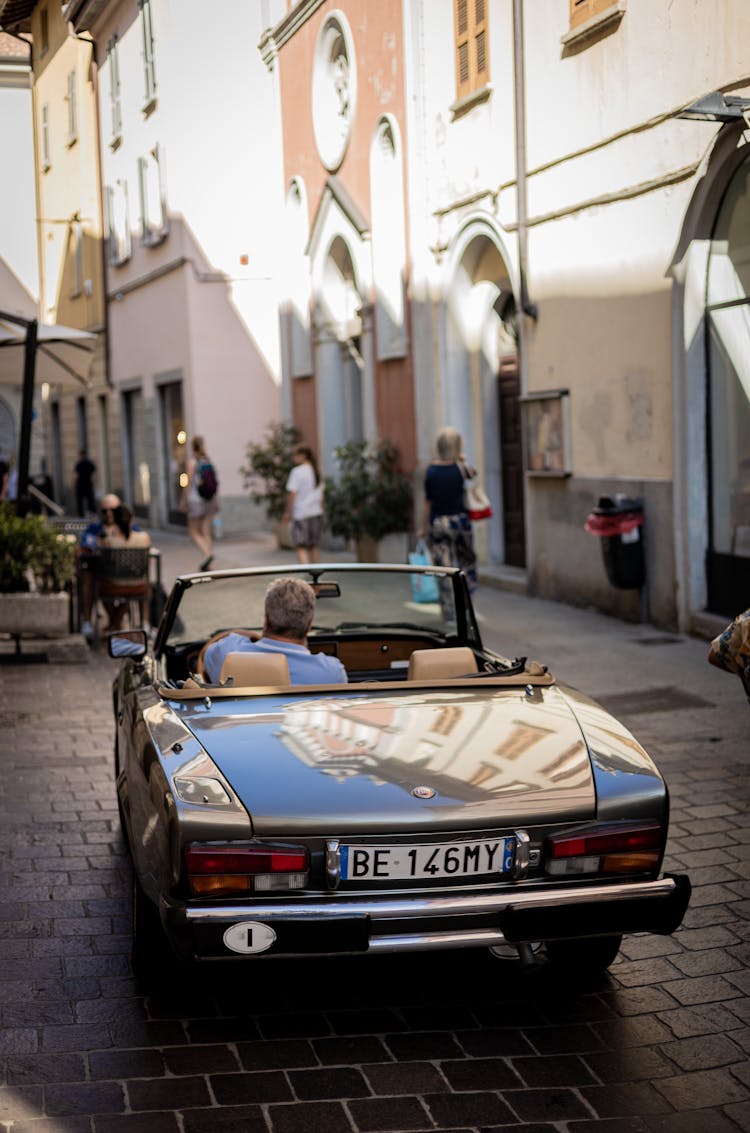 Man Driving A Vintage Convertible Car In A City 