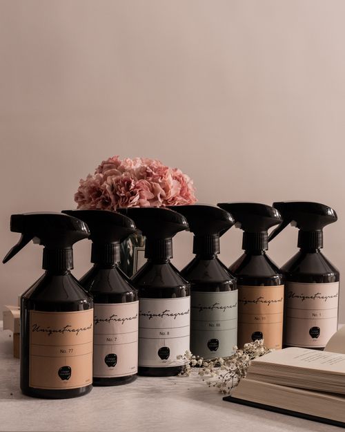 Free Stylish lineup of diverse fragranced bottles with flowers and a book in a serene setting. Stock Photo