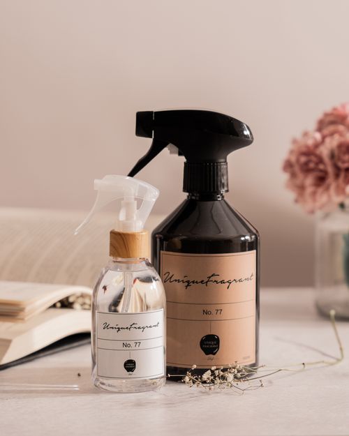 Free Stylish spray bottles alongside an open book and pink flowers, exuding elegance and tranquility. Stock Photo