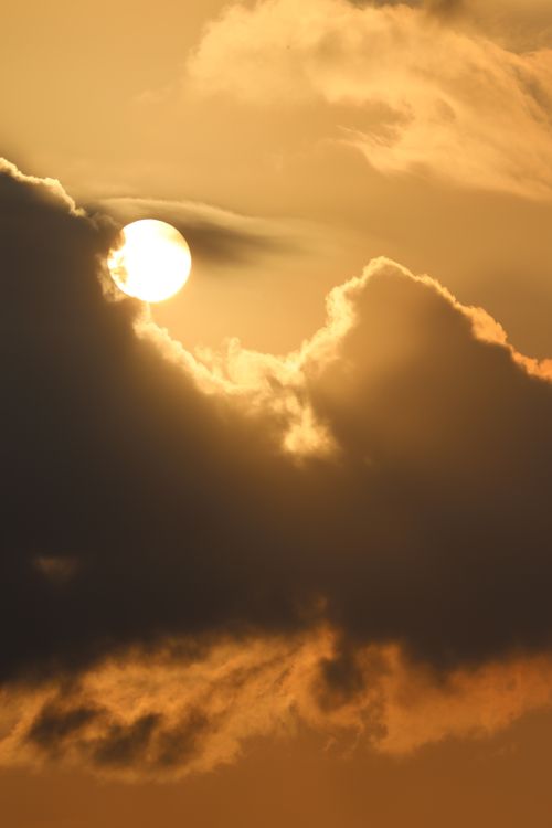 Free Golden sun setting behind dramatic clouds, creating a stunning sky scene. Stock Photo