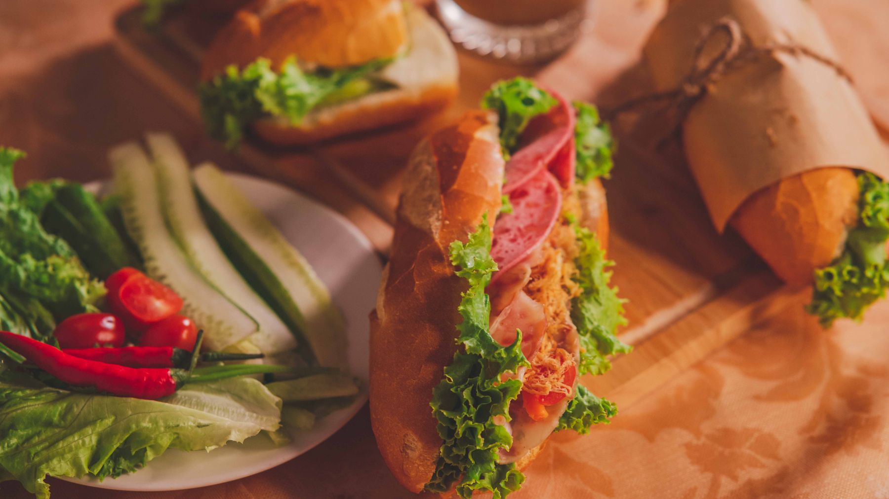 테이블 위에 신선한 채소와 함께 놓인 맛있는 베트남 Banh Mi 샌드위치 클로즈업.